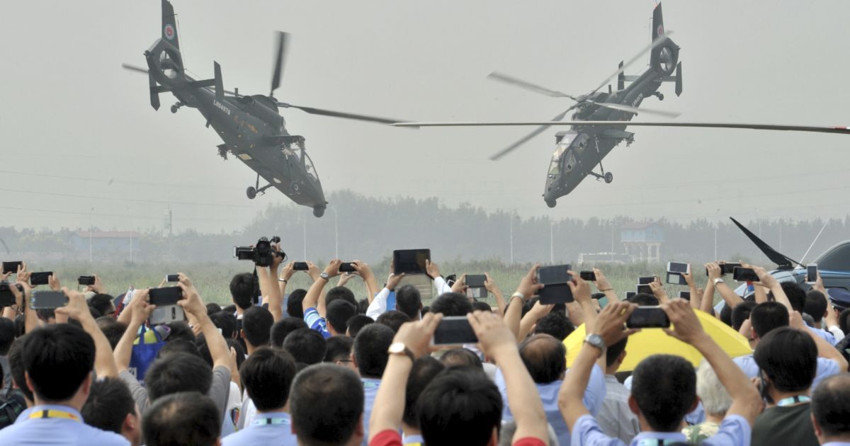 Зрители фотографируют на телефоны маневры вертолетов во время выставки военной техники в Китае / © Reuters