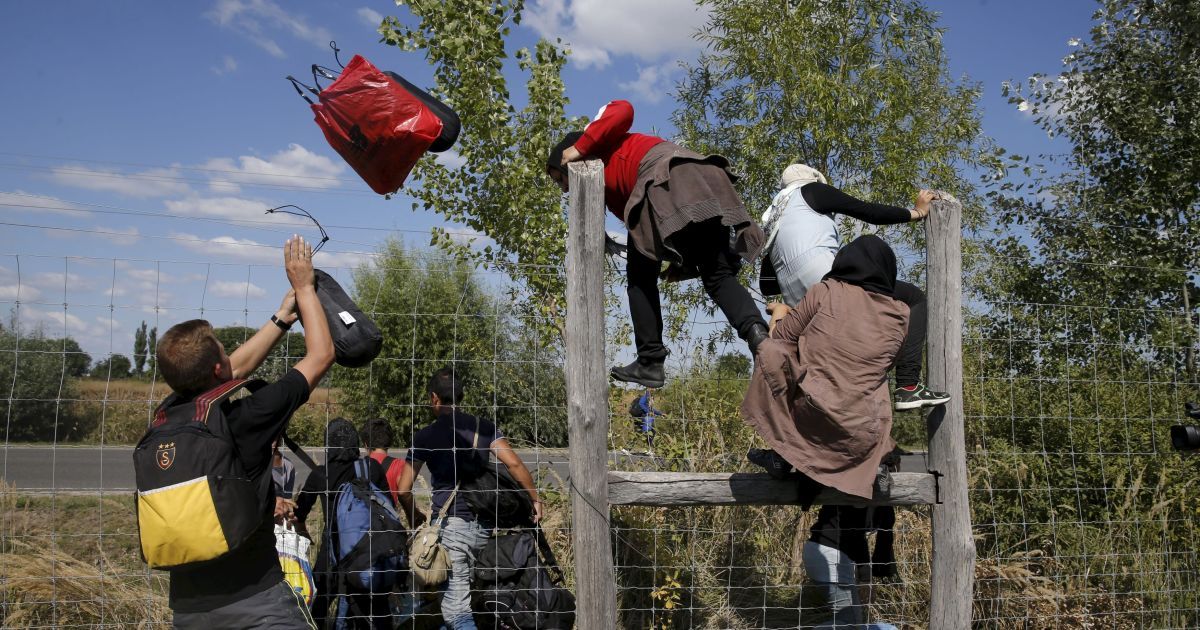 Мигранты перепрыгивают через забор, убегая из лагеря беженцев в Венгрии. С начала года в Европу приехали 365 тысяч беженцев, большинство которых &ndash; из Сирии, где продолжается война / © Reuters