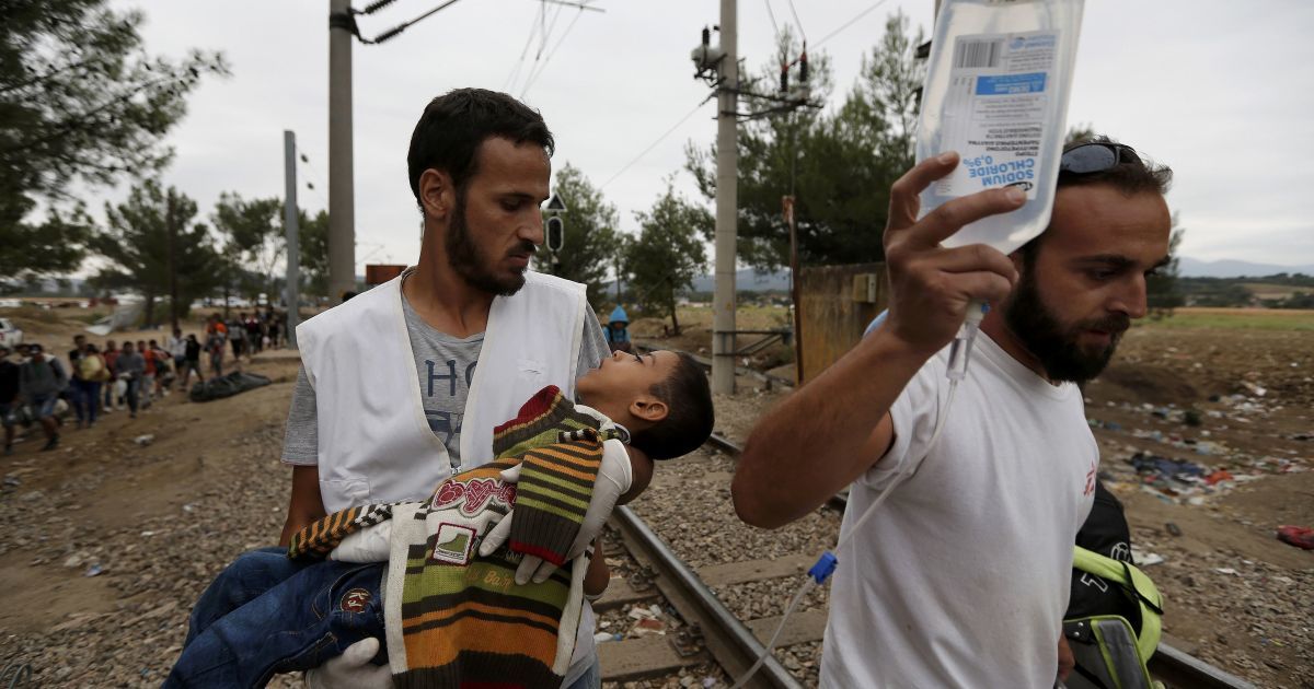 Медики несут тяжелобольного сирийского мальчика-беженца в лагере мигрантов на границе Греции и Македонии. С начала года в Европу приехали 365 тысяч беженцев, большинство которых &ndash; из Сирии, где продолжается война / © Reuters