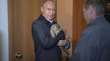Президент России Владимир Путин держит на руках кошку в новом доме в селе Краснополье в Сибири. Перед этим дома людей полностью уничтожил масштабный пожар / © Reuters