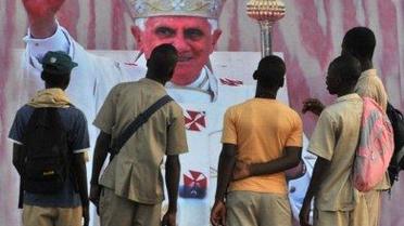 Бенін, Уїда. Діти дивляться на портрет Папи Римського Бенедикта XVI, який вивісили на вулиці напередодні візиту понтифіка в Бенін. Папа Римський вирушає у триденний візит для зустрічі з католицькими лідерами і паломниками з усього континенту. / © AFP