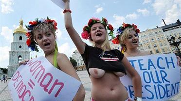 Україна, Київ. Активістки жіночого руху FEMEN тримають плакат і листа до державного секретаря Гілларі Клінтон, яка 2 липня розпочала офіційний візит до України. Під час проведення "голої" акції на Софійській площі у Києві активістки FEMEN звернулись до держсекретаря з проханням навчити український уряд гендерній рівності та демократії. / © AFP